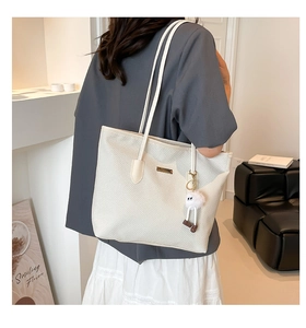 Detailed texture of white woven tote bag with slim straps and cute plush pendant