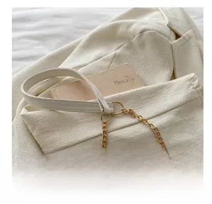 Detail of white leather shoulder strap with gold chain links and metallic hardware