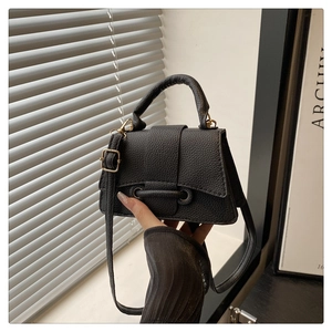 Detail of black lychee grain faux leather shoulder bag with top handle and metal buckle strap