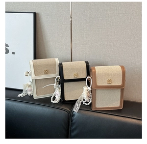 Close-up of canvas mini bags with leather trim, golden flower logo and pearl charms