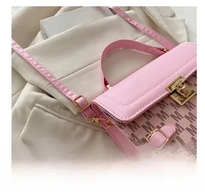 Detail of pink embroidered crossbody bag with M pattern and golden rotating metal lock