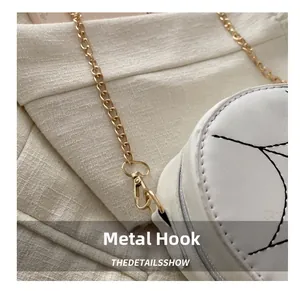 Close-up of golden metal chain and lobster clasp on white faux leather shoulder bag