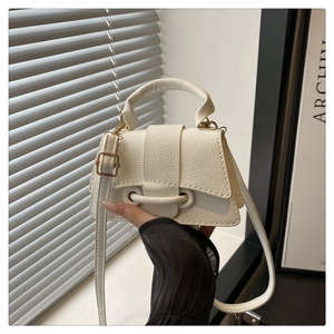 Detail of white lychee leather texture on crossbody bag with metal ring closure buckle