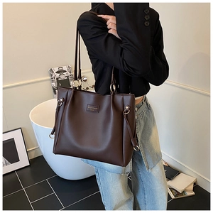 Deep brown tote bag detail showing matte leather texture and drawstring on person