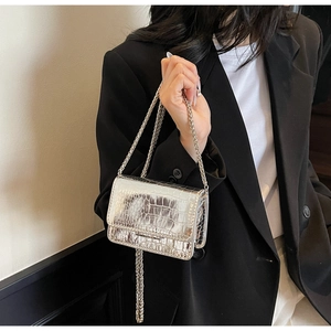 Silver crocodile texture mini bag with chain strap worn over a black blazer