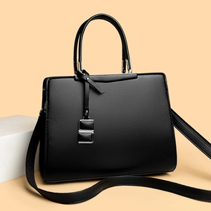 Détail d'un sac à main noir en cuir texturé avec boucle argentée et bandoulière amovible