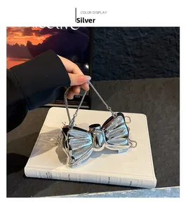 Dettaglio pochette a forma di fiocco argento metallizzato con finitura a specchio lucida