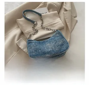 Detailed close-up of blue tweed texture and silver chain strap on denim shoulder bag