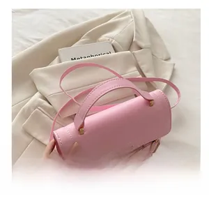 Detail of pink crossbody bag with metal buckle and monogram pattern held by a model