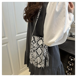 Detail of crossbody bag with black and white snake print and fringe on a model