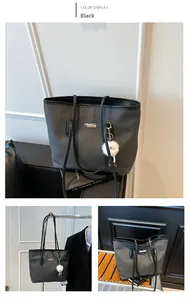 Dettaglio borsa tote nera intrecciata con placca dorata e ciondolo in peluche