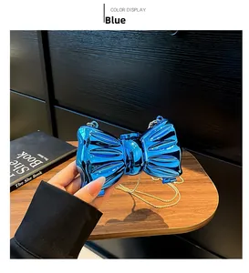 Dettaglio della borsa a fiocco blu metallizzato con catena dorata in mano