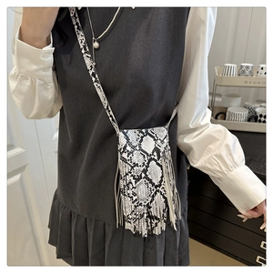 Detail shot of the black and white snakeskin texture and long tassels on this crossbody bag