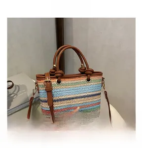 Detail of colorful woven straw handbag featuring brown leather handles and gold eyelets