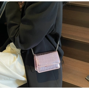 Detail of pink croc-embossed leather mini bag with silver chain strap on model
