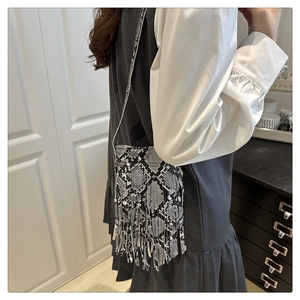 Detail of snake skin print crossbody bag with tassel and slim shoulder strap