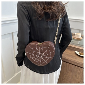 Brown heart-shaped crossbody bag with spider web embroidery and gold chain on model
