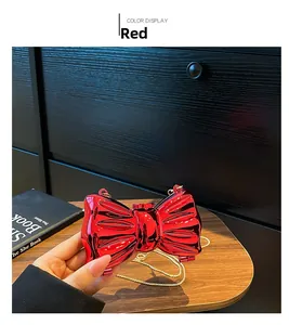Dettaglio pochette rossa a fiocco in acrilico con catena dorata e trama effetto seta