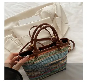 Detail of multi-color woven tote bag featuring brown leather handles and knot accents
