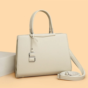 Détail du sac à main crème en cuir synthétique avec grain de lychee et pendentif en S