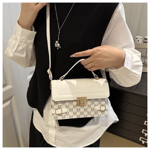 Detail of white leather handbag with gold clasp and repeated M letter pattern textile