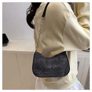 Detail of dark gray denim shoulder bag with sparkling rhinestones and silver chain strap