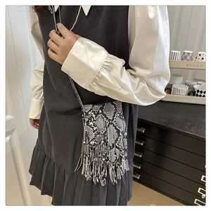 Detail of bohemian mini crossbody bag featuring snake pattern leather and long tassels