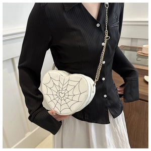 White heart-shaped crossbody bag with spider web stitching and gold chain strap