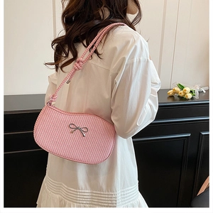 Pink woven shoulder bag with bow detail shown on model from back view
