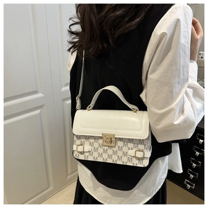 Detail of trendy color-block crossbody bag featuring gold hardware and monogram patterns