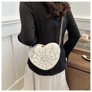 Detail of white heart crossbody bag with spider web embroidery and gold chain strap