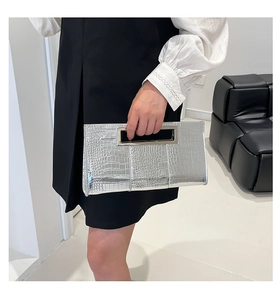 Detail of silver crocodile-embossed clutch bag with rectangular metal handle