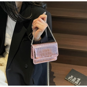 Close-up of metallic pink mini bag with crocodile texture and silver chain strap