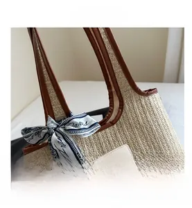 Detailed view of woven straw tote bag with brown leather trim and Paris silk scarf accent