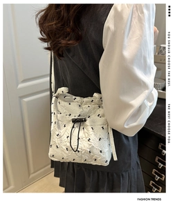 Detail of white quilted texture with black bow print and drawstring closure on bag