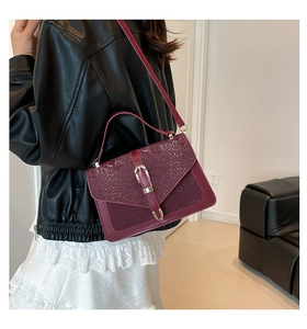 Detail of wine red crossbody bag with snake skin pattern texture and golden metal clasp