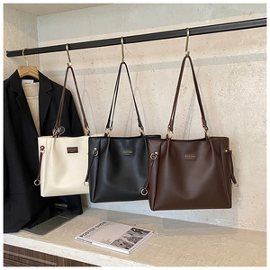 Detailed view of large minimalist leather tote bags in cream, black, and coffee brown