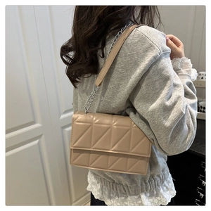 Detailed view of beige quilted leather chain bag worn over the shoulder by a model