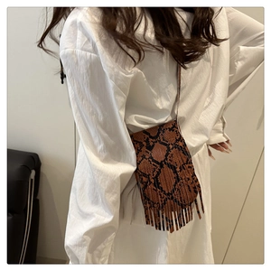 Detail of brown snakeskin crossbody bag featuring dense long tassels and bohemian style