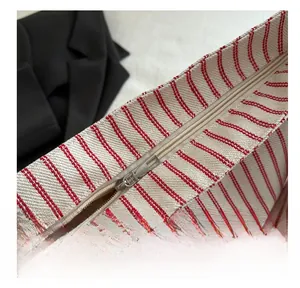 Close-up of smooth silver zipper and red striped canvas texture on the tote bag