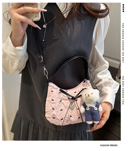 Détail du sac bandoulière plissé rose avec nœuds noirs et breloque petit ours