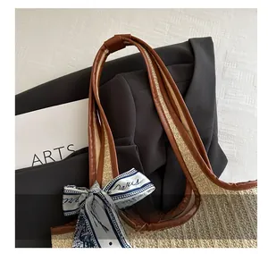 Detail of woven straw tote bag with brown PU handle and a stylish Paris print silk scarf