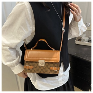 Close-up of vintage brown leather handbag with M-pattern print and metal buckle