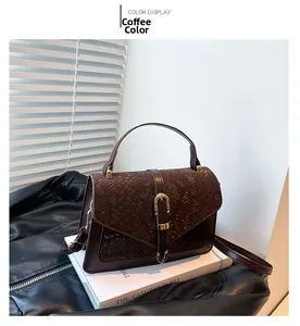 Detail of coffee brown faux snake skin bag with metal buckle on white books in soft light