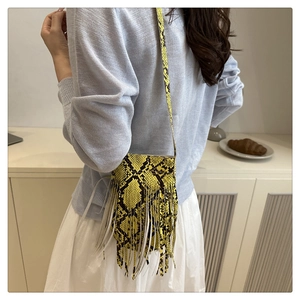 Chic yellow snakeskin crossbody bag with white leather fringe details shown on a model