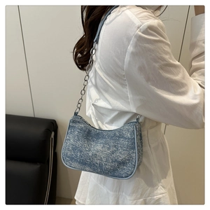 Detail of blue denim fabric moon bag with silver chain and leather shoulder strap