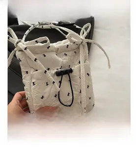 Detail view of the white quilted bucket bag with black bunny prints and drawstring closure