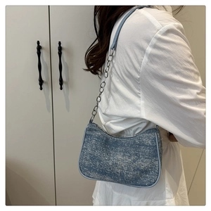 Close-up of light blue denim shoulder bag with silver sparkles and chain strap detail