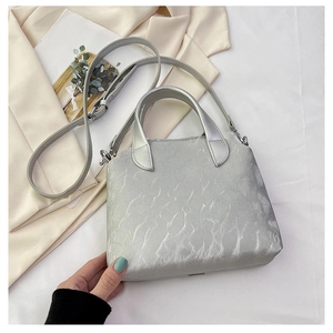 Silver metallic textured handbag on beige blazer with minimalist lifestyle background