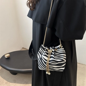 Detail of zebra pattern bucket bag with pearl drawstring and golden chain strap